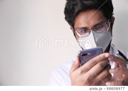 Male doctor in white coat is using a modern smartphone device 68608977