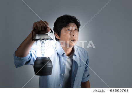 暗い世の中をランタンを持って出口を探す中年男性 暗い世の中をランタンを持って出口を探す中年男性 68609763