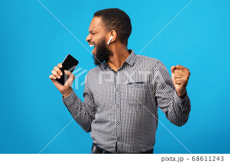 Happy afro man singing using smartphone as mic 68611243