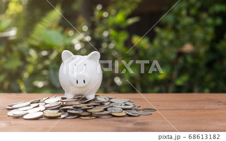 Piggy bank and money coins pile on wood table Piggy bank and money coins pile on wood table 68613182