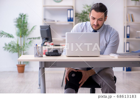 Young leg injured employee working in the office Young leg injured employee working in the office 68613183