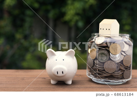 Piggy bank and house model on money coins glass Piggy bank and house model on money coins glass 68613184