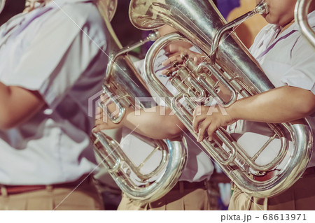 Male student with friends blow the euphonium with the band for performance on stage at night. 68613971