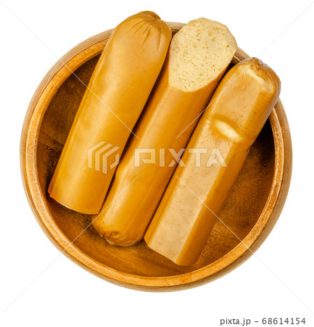 Vegan Vienna sausages in wooden bowl. Thin parboiled sausages, made of tofu then given a low temperature smoking. Also called Wiener or Frankfurter Wuerstl. Close-up from above over white, food photo. Vegan Vienna sausages in wooden bowl. Thin parboiled sausages, made of tofu then given a low temperature smoking. Also called Wiener or Frankfurter Wuerstl. Close-up from above over white, food photo. 68614154