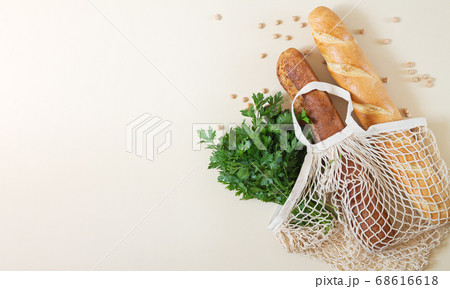 Mesh shopping bag with baguettes and fresh herbs top view with space for your text Mesh shopping bag with baguettes and fresh herbs top view with space for your text 68616618