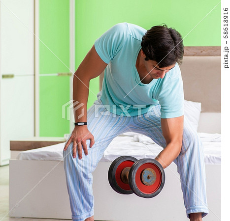 Young man in pajamas doing morning exercises Young man in pajamas doing morning exercises 68618916