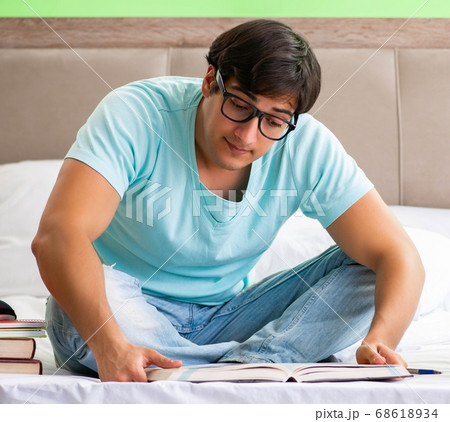 Student preparing for exams at home in bedroom sitting on the be 68618934