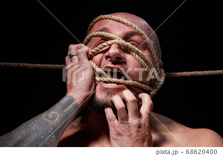 Photo of binded bald man trying tear the rope on face 68620400