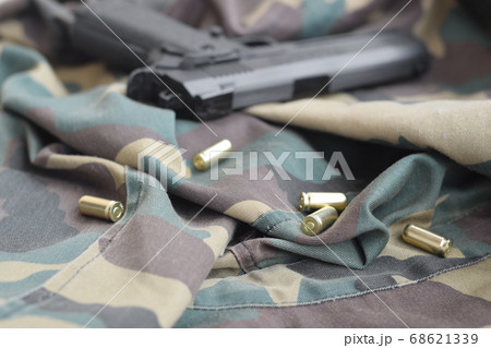 9mm bullets and pistol lie on folded camouflage 68621339