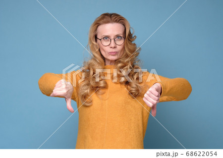 Gloomy dissatisfied mature woman looks at camera show thumbs down. Gloomy dissatisfied mature woman looks at camera show thumbs down. 68622054