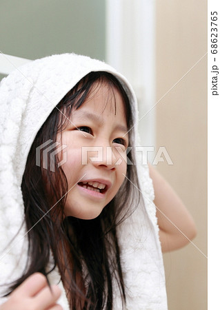 お風呂上がりにバスタオルで髪の毛を拭く女の子の写真素材