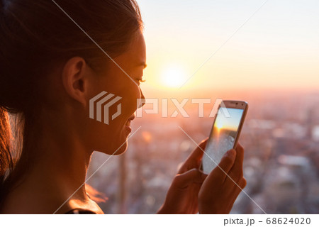 Woman tourist looking at phone pictures of sunset view of Europe travel destination. Asian girl using cellphone camera app in London Shard Tower, UK. Mobile photography taking photos Woman tourist looking at phone pictures of sunset view of Europe travel destination. Asian girl using cellphone camera app in London Shard Tower, UK. Mobile photography taking photos 68624020