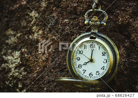 Vintage old pocket watch hanged on the rock background. At 8 o'clock. Closeup and copy space. 68626427