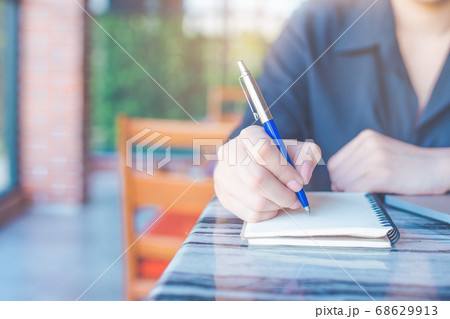 Woman is writing on a notebook with a pen Woman is writing on a notebook with a pen 68629913