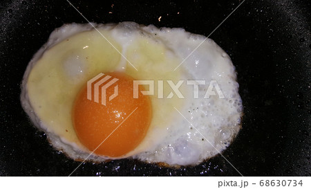 fried eggs from one egg on a black frying pan 68630734