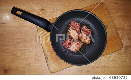 photo of pieces of bacon on a black frying pan on 68630735