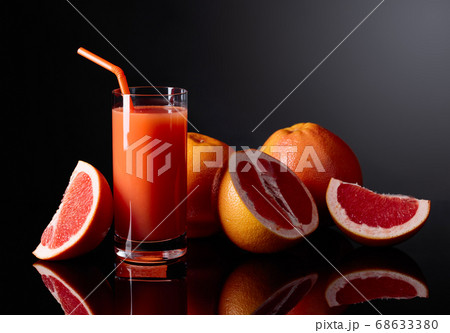 Glass of grapefruit juice and cut fruits on black Glass of grapefruit juice and cut fruits on black 68633380