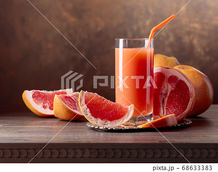 Glass of fresh grapefruit juice and cut fruits . 68633383