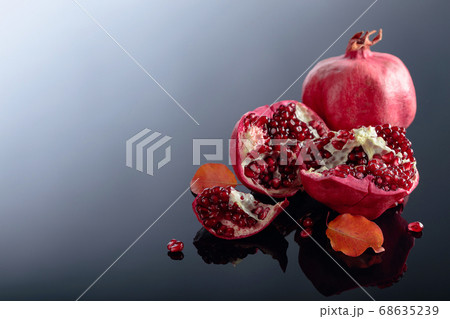 Ripe pomegranate fruits on a black reflective Ripe pomegranate fruits on a black reflective 68635239
