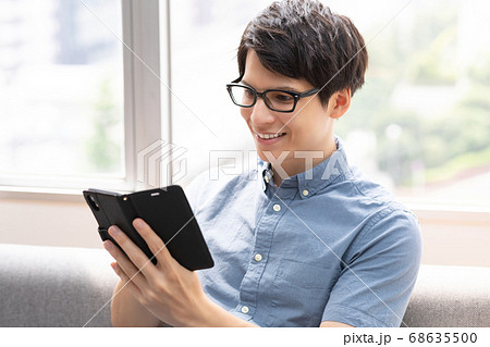 ソファーでスマホをみる男性 写真素材 ソファーでスマホをみる男性 写真素材 68635500
