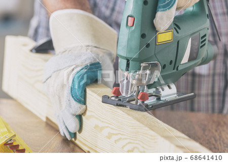 Cutting a piece of wood using a jigsaw 68641410