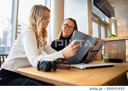 Serious Young Bloggers Discussing Over Publication In Cafe 68643493