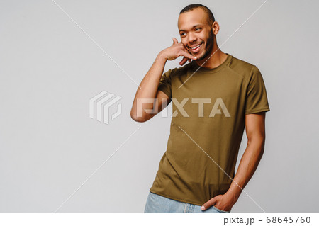 Handsome young African American man showing a call me sign and smiling while standing isolated on grey background Handsome young African American man showing a call me sign and smiling while standing isolated on grey background 68645760