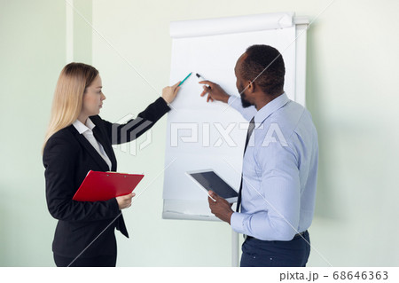 Young businessman working with colleague using flipchart, copyspace 68646363