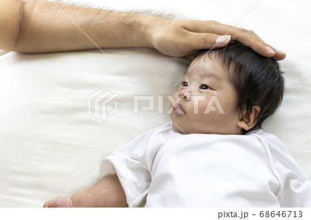 赤ちゃんの頭を撫でる男性の手の写真素材
