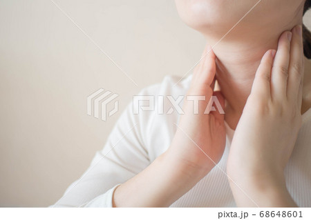 Female checking thyroid gland by herself. Close up of woman in white t- shirt touching neck. Thyroid disorder includes goiter, hyperthyroid, hypothyroid, tumor or cancer. Health care. Copy space. 68648601