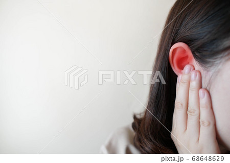 Young woman suffering from ear pain and tinnitus. Cause of earache includes otitis, earwax buildup, a foreign object in the ear, sinus infection or changes in air pressure. Ear disease concept. 68648629