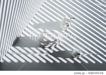 Still life with three white vials and diagonal striped shadow 68649338