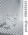 Still life with a glass mug and diagonal striped shadow 68649345