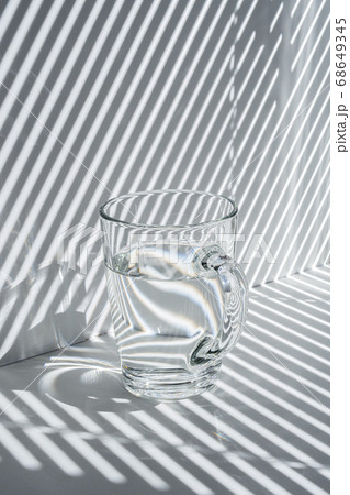 Still life with a glass mug and diagonal striped shadow 68649345