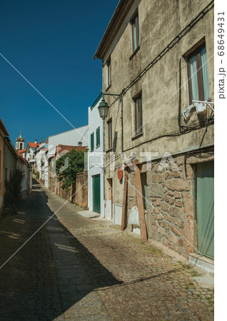 Old house with worn plaster wall and narrow alley 68649431