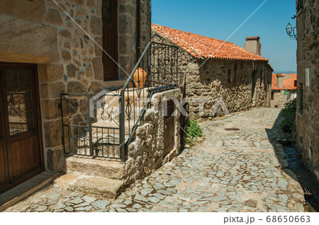 Cobblestone alley on slope and stone old houses 68650663
