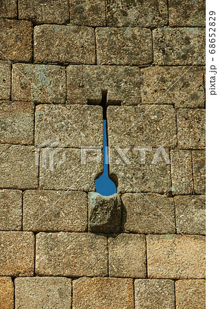 Narrow slit in cross shape and gutter on a stone wall 68652829