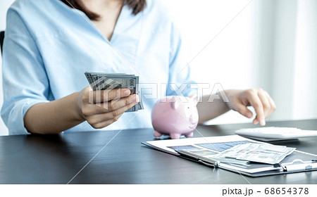 woman's hand holding dollar note and piggybank on table, Saving money for future plan and retirement woman's hand holding dollar note and piggybank on table, Saving money for future plan and retirement 68654378