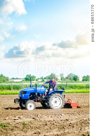 The farmer drives a tractor with a milling unit equipment. Loosening land cultivation Use of agricultural machinery to speed up work. Farming. Plowing field. The stage of preparing soil for planting. The farmer drives a tractor with a milling unit equipment. Loosening land cultivation Use of agricultural machinery to speed up work. Farming. Plowing field. The stage of preparing soil for planting. 68655770