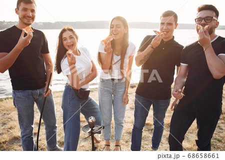 Young people eating pizza smoking hookah outside 68658661