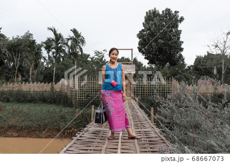 Beautiful Thai woman wearing old Thai traditional cloth standing on bamboo bridge. 68667073