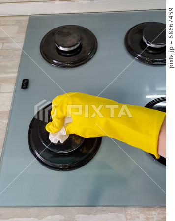 Hand in protective gloves cleans the gas stove with a rag Hand in protective gloves cleans the gas stove with a rag 68667459