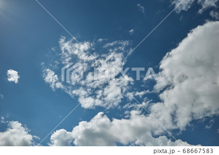 The sun's rays lit up a blue sky covered with torn cumulus clouds 68667583
