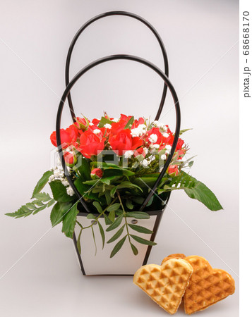 Heart shaped cookies and a basket of roses. 68668170