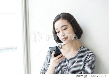 スマートフォンと若い女性　部屋で寛ぐ女性　イメージ素材 68670593
