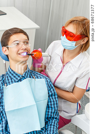 Beautiful woman dentist treating teeth in dental 68671377