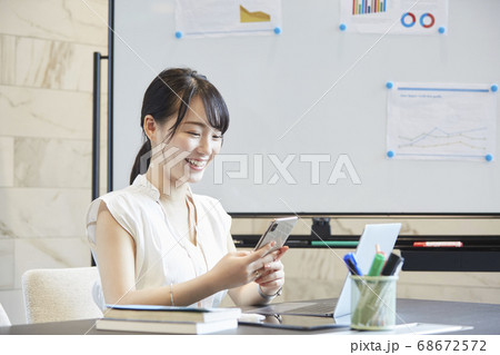 会議中にスマートフォンを操作する女性 会議中にスマートフォンを操作する女性 68672572