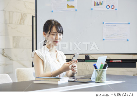 会議中にスマートフォンを操作する女性 会議中にスマートフォンを操作する女性 68672573