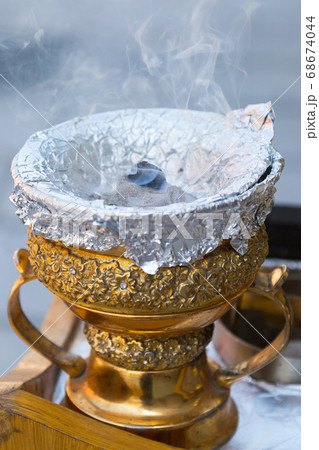 Fragrant smoke comes out of a golden vase. 68674044