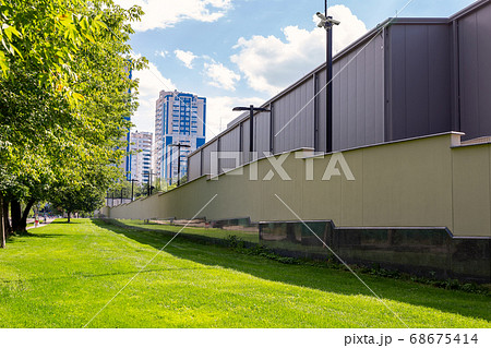 Green grass lawn and secured high fenced area with secutity cctv cameras ofresidential apartment , office of industrial building. Tall wall protected safety zone district in crime city 68675414